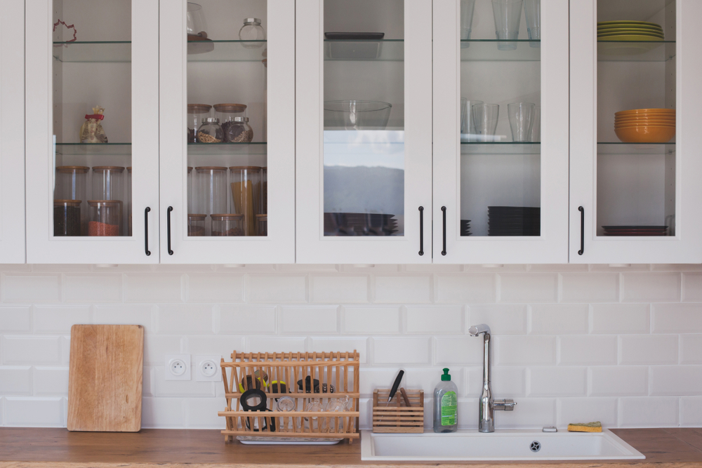 interior of modern white kitchen in scandinavian style, cupboards with glass doors 